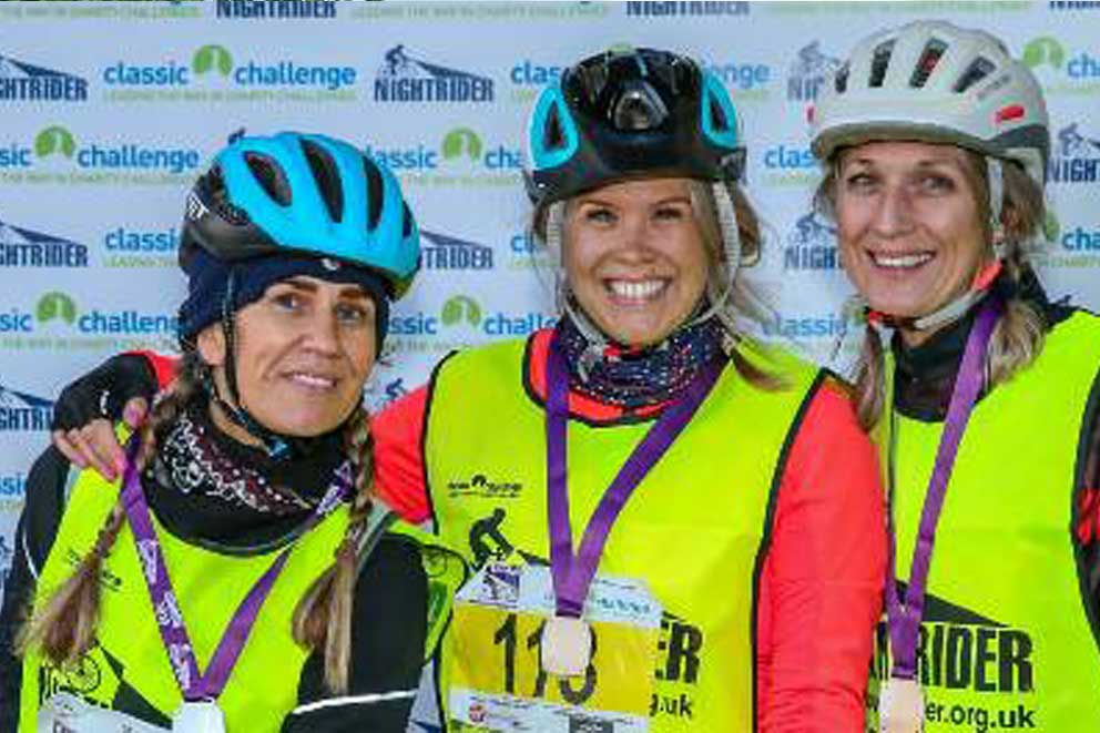 Three cyclists showing off their race event medals.
